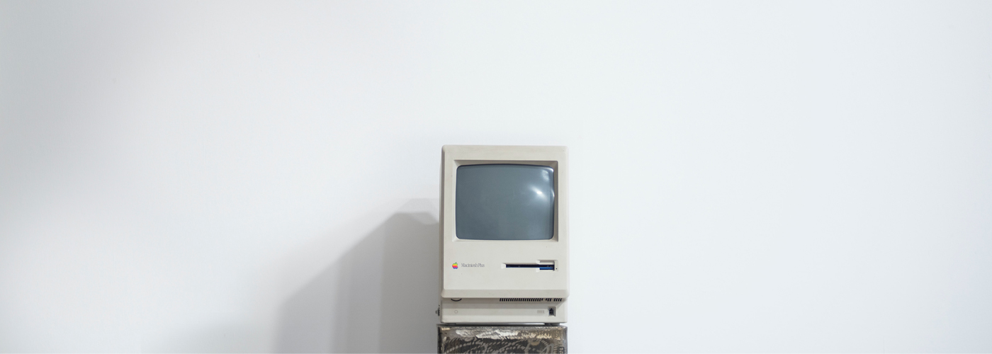 An old computer from the 1980s sites in front of a stark white background, like a scene from a museum.