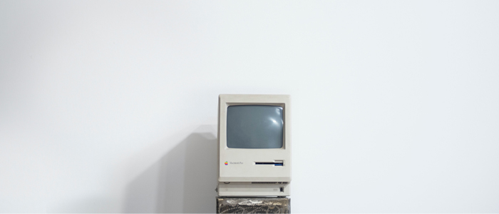 An old computer from the 1980s sites in front of a stark white background, like a scene from a museum.