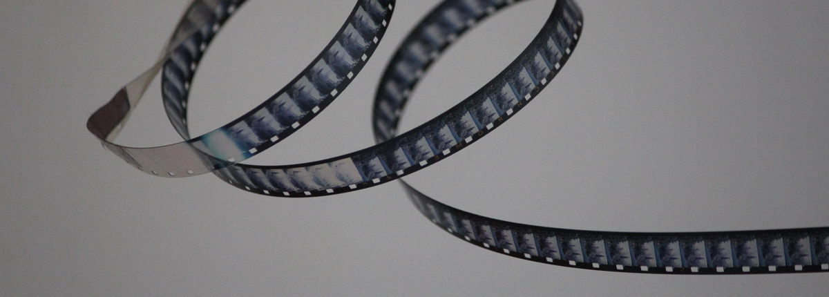 A reel of film curls in over itself twice forming a loop with the final strand of film flying out of frame to the right. Photo by Denise Jans.