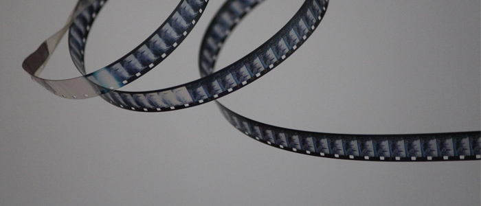 A reel of film curls in over itself twice forming a loop with the final strand of film flying out of frame to the right. Photo by Denise Jans.